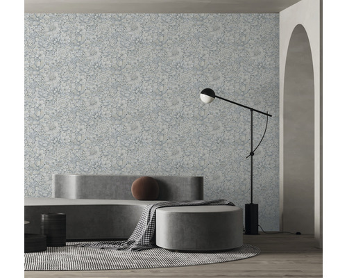 Wohnraum mit floral gemusterter Tapete, Sofa, Hocker und Stehlampe