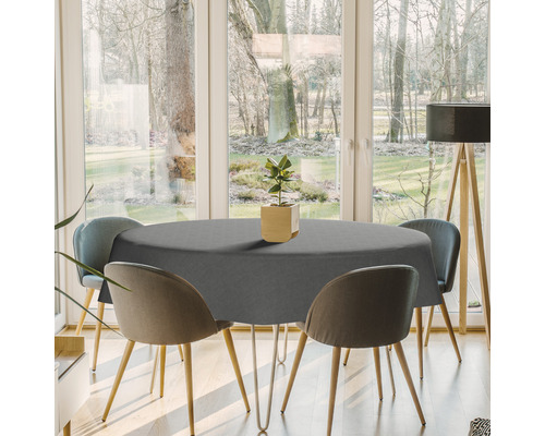 Table de salle à manger avec nappe grise et chaises dans une pièce lumineuse.