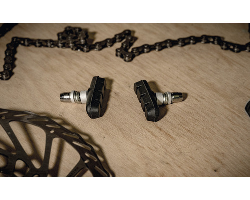 Fahrradbremsbeläge neben Fahrradkette und Bremsscheibe