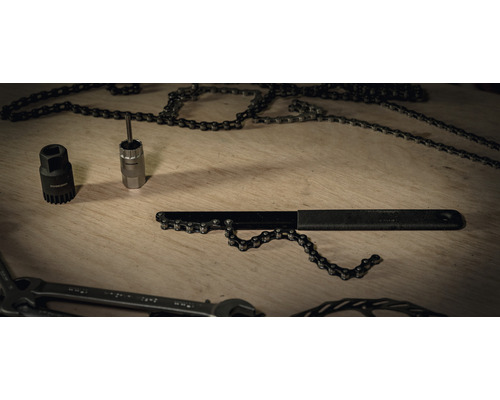Fahrradwerkzeug mit Kettennietdrücker und Kettenpeitsche auf einem Holztisch