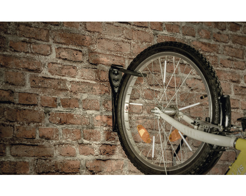 Vélo sur un support mural devant un mur en briques
