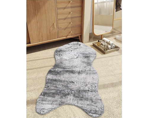 Fausse fourrure décorative gris-blanc devant une armoire en bois et un miroir