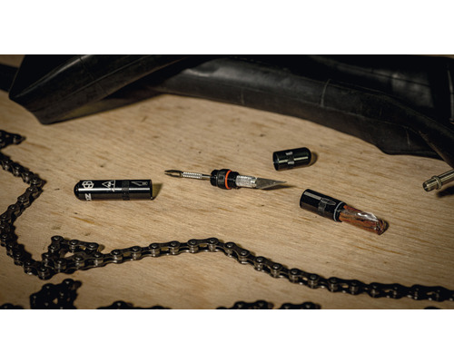 Kit de réparation de vélos avec pneu, chaîne et outils sur une table en bois.