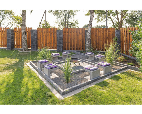 Scène de jardin avec foyer, sièges avec coussins et clôture en bois