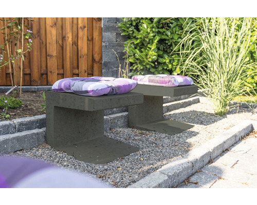 Zwei graue Gartenbänke aus Beton mit Sitzkissen im Aussenbereich.