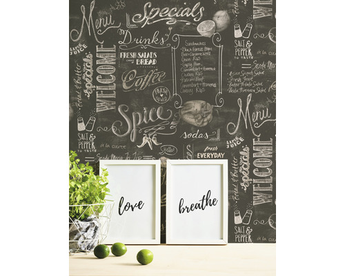 Dekorative Tafel-Tapete mit Kreide-Schriftzug in einem Raum mit Topfpflanze und Bilderrahmen