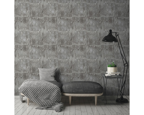 Graue Ziegel-Tapete in einem stilvollen Wohnzimmerambiente mit Lampe, Sitzhocker und Kissen.