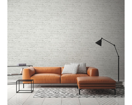 Salon avec canapé, tabouret, lampe et papier peint à motif de briques