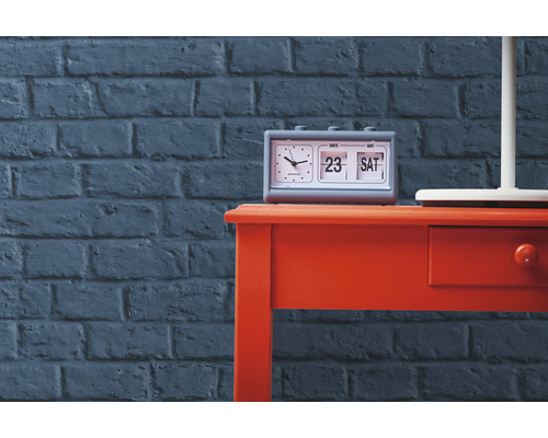 Tisch mit Klappzahlenwecker vor Ziegelwand