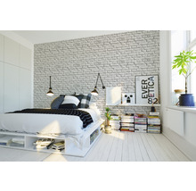 Schlafzimmer mit Bett, Nachttisch und Ziegelwandtapete