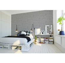 Chambre claire avec lit et papier peint en briques grises