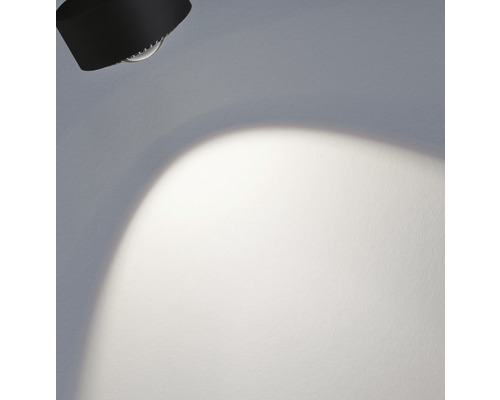 Schwarzer Deckenstrahler leuchtet auf eine Wand
