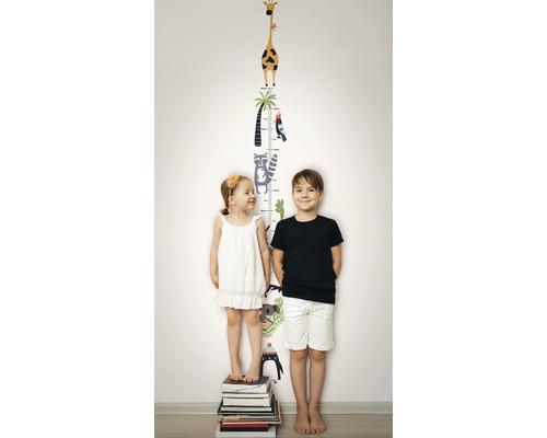 Deux enfants se tiennent devant un autocollant mural avec une échelle de croissance et des motifs d''animaux.