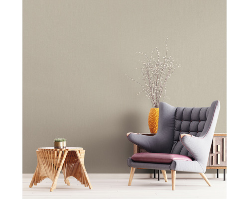 Wohnzimmer mit beiger Tapete, Sessel und Holztisch