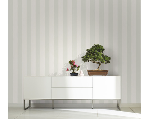 Vue d''une pièce avec papier peint rayé, buffet blanc et décoration avec des bonsaïs