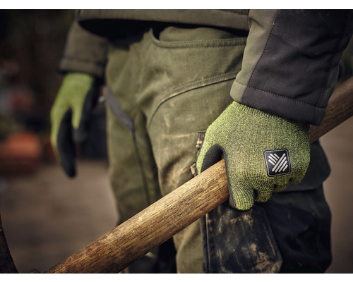 Un homme tient un manche en bois avec des gants de travail