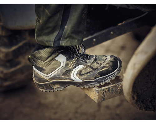Une chaussure de travail sale se trouve sur une marche en métal