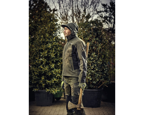 Homme en vêtements de travail avec une hache dans le jardin.