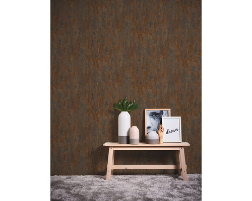 Dekoratives Interieur mit einer Tapete mit Rosteffekt, einem Holzbänkchen und Accessoires.