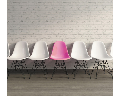 Reihe von Stühlen mit einem einzelnen farbigen Stuhl vor einer Wand