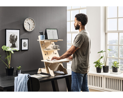 Stehpult aus Holz mit einer Person, die daran arbeitet, in einem hellen Raum.