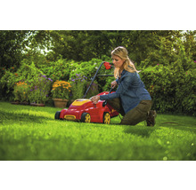 Eine Frau bedient einen Rasenmäher im Garten.