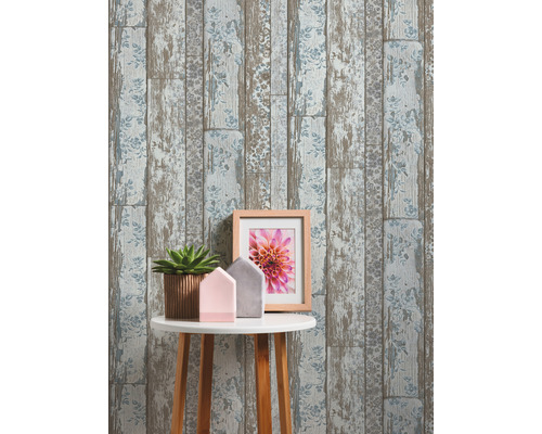 Dekorative Tapete mit Holzplankenoptik und Blumenmuster hinter einem Tisch mit Dekoration