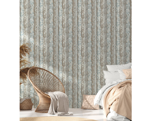 Dekoratives Schlafzimmer mit einer Wandtapete in Holzoptik, einem Sessel und einem Bett.