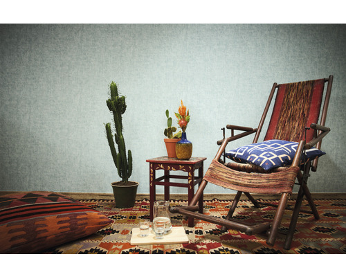 Wohnzimmer mit Sessel, Teppich, Kissen, Tisch und Kakteen