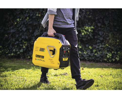 Une personne transporte un générateur onduleur Champion de 2200 watts jaune à l''extérieur.