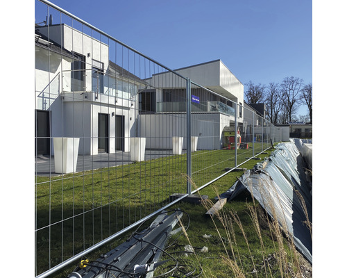 Baustellensicherung mit Bauzaun vor einem modernen Gebäude.