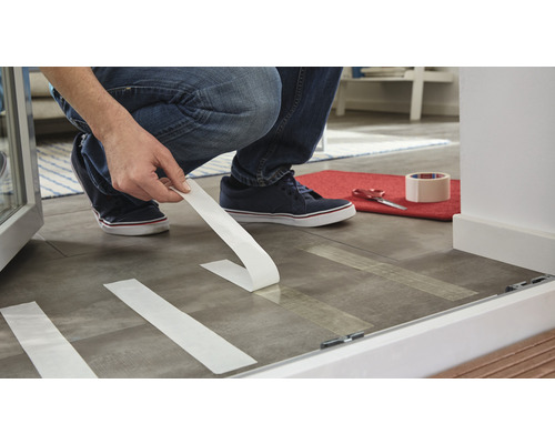 Personne collant du ruban adhésif sur le sol