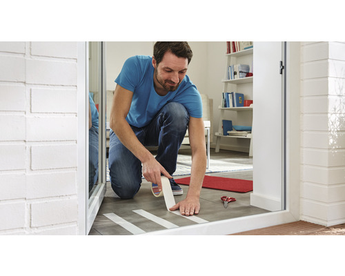 Homme collant du ruban de masquage sur un sol carrelé