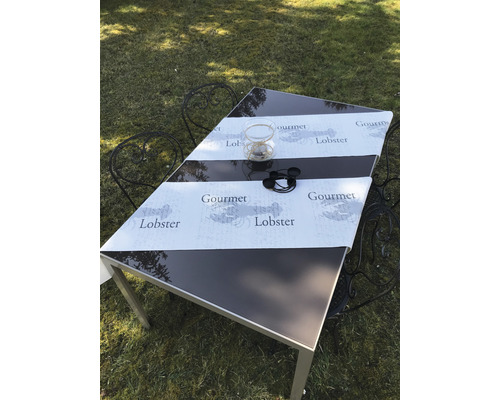 Gartentisch mit Tischläufer, Dekoration und Stühlen auf einer Rasenfläche