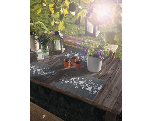 Table de jardin avec sets de table, tasses, compositions florales et lanternes