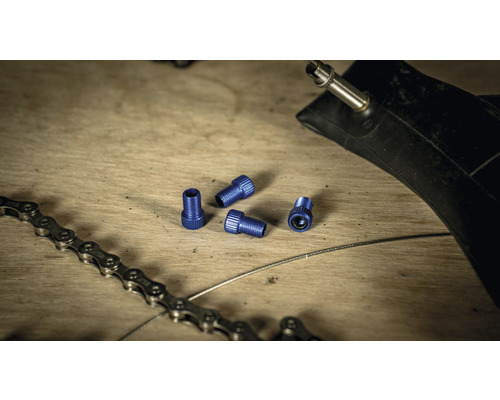 Chambre à air de vélo, chaîne de vélo et bouchons de valve sur une table en bois