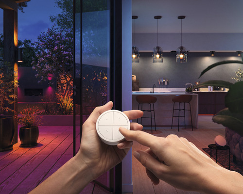 Szene mit einer Person, die einen Lichtschalter vor einer beleuchteten Terrasse und einer Innenküche bedient