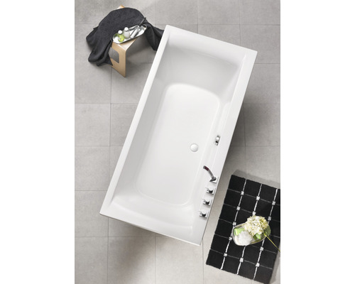 Baignoire rectangulaire dans une salle de bain avec robinetterie et décoration