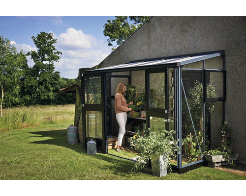Serre avec des plantes et une femme dans le jardin.