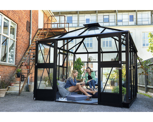 Serre avec parois en verre et cadre noir dans le jardin