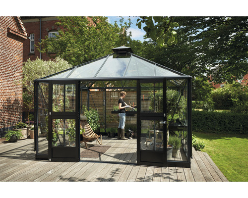 Serre avec verre, porte et terrasse en bois dans le jardin.