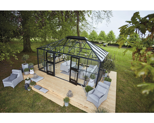 Une serre avec des sièges sur une terrasse en bois dans un jardin.