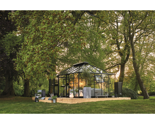 Serre sur une plateforme en bois dans un jardin avec des arbres