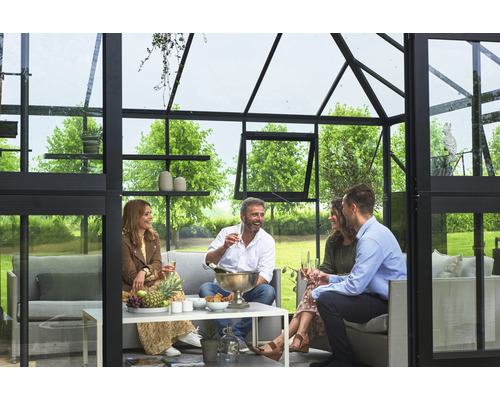 Un groupe de personnes profite d''une réunion conviviale dans une serre avec des sièges et une table.