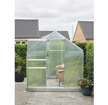 Gewächshaus mit geöffneter Tür auf einer Terrasse mit Gartenmöbeln und Pflanzen