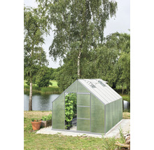 Gewächshaus im Garten mit Pflanzen und Teich im Hintergrund