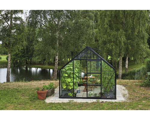 Serre dans le jardin avec plantes, table et chaises