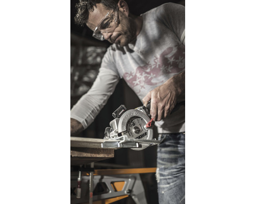 Un homme scie une planche de bois avec une scie circulaire portative Worx