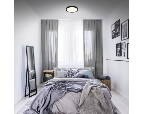 Schlafzimmer mit Bett, Vorhängen und runder Deckenleuchte