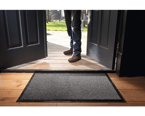 Paillasson devant une porte d''entrée ouverte sur un plancher en bois